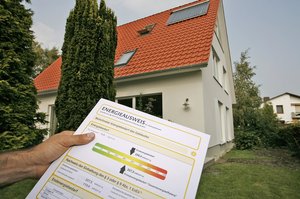 Ein Energieausweis vor dem Hintergrund eines Einfamilienhauses. Foto: Deutsche Energie-Agentur GmbH (dena)