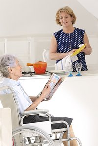 Eine Haushaltshilfe wäscht das Geschirr bei einer Seniorin. Foto: © Jean-Paul CHASSENET Photographe