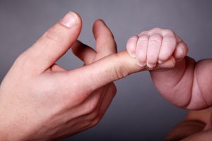 Babyhand greift Finger eines Erwachsenen. Foto: © Nick Freund - Fotolia.com