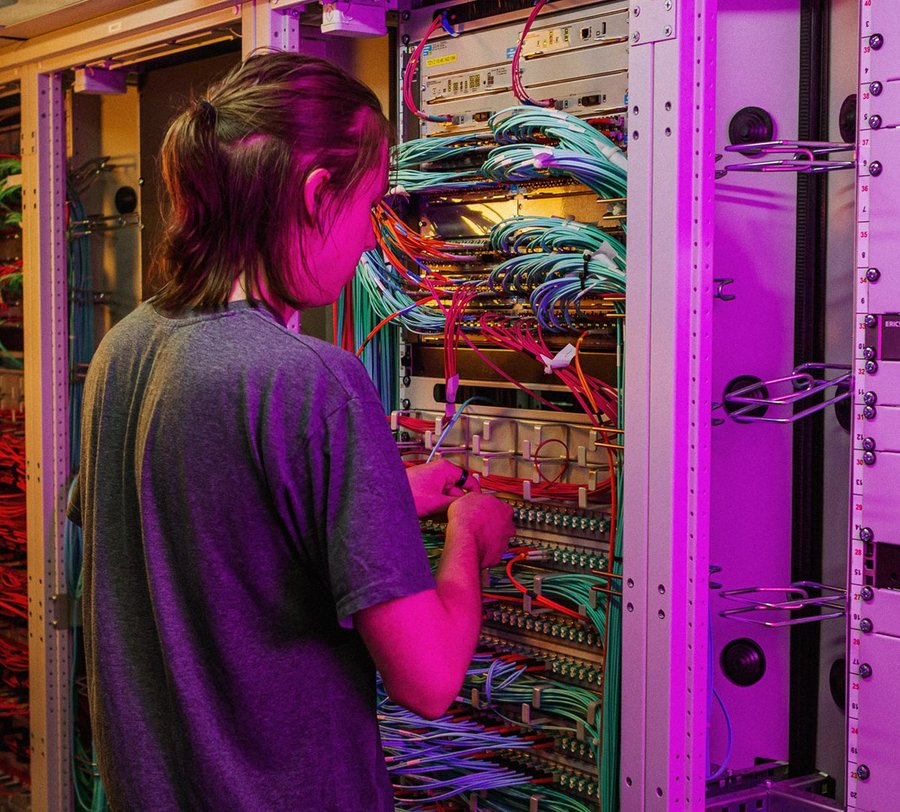 Ein Mann kontrolliert die vielen verschiedenen Kabel in einem Serverraum. Foto: Thomas Grimm