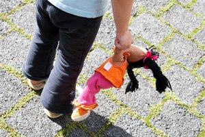 Kleines Mädchen lässt eine Puppe hängen. Foto: © Bobo - Fotolia.com